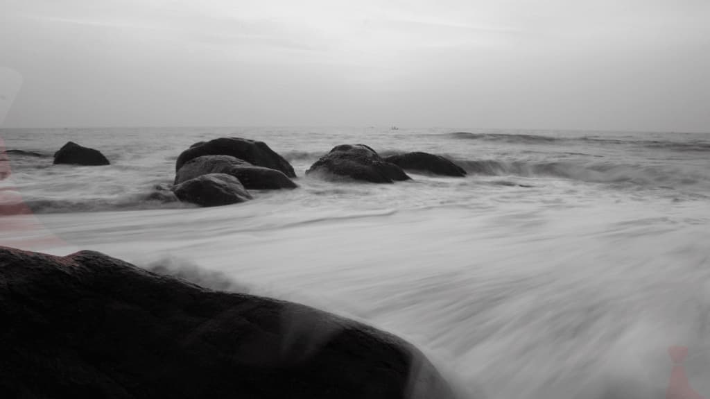 black-and-white long exposure of waves washing over rocks