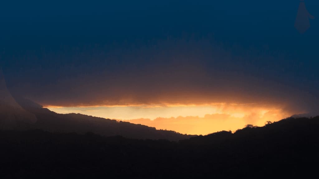 sunset glow behind a dark mountain ridge