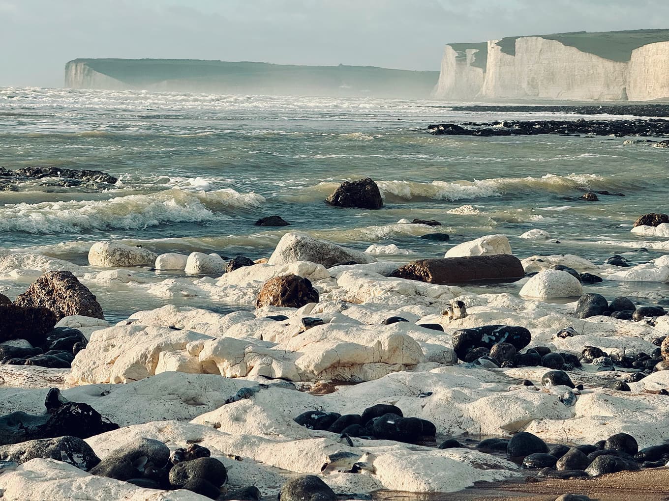 white chalk cliffs and boulders on a wave-washed shore