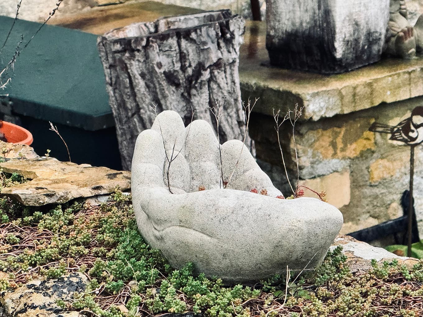 a stone sculpture of an open hand in a garden
