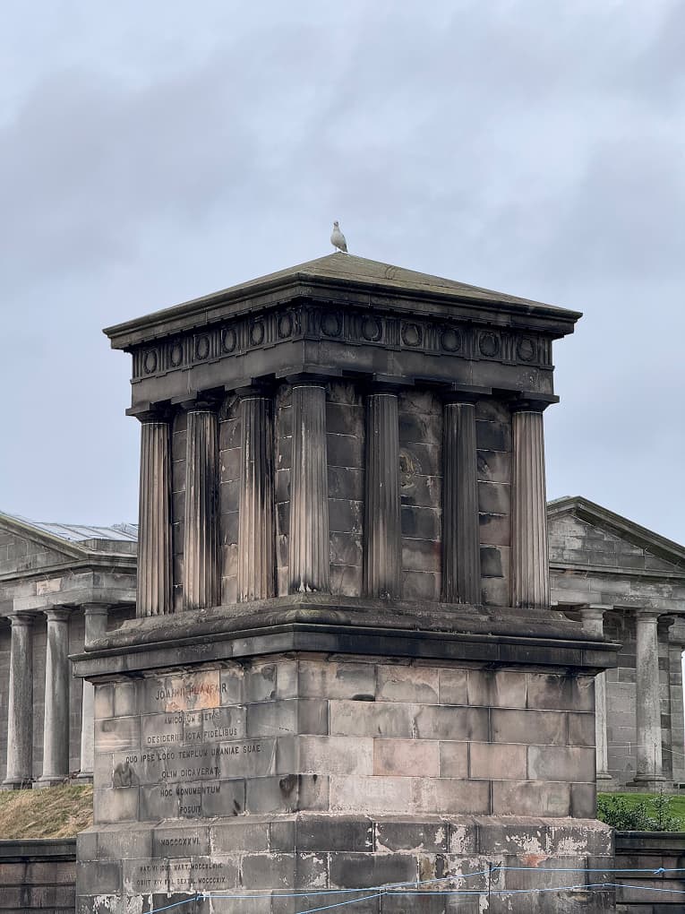 a neoclassical stone monument with columns under a grey sky
