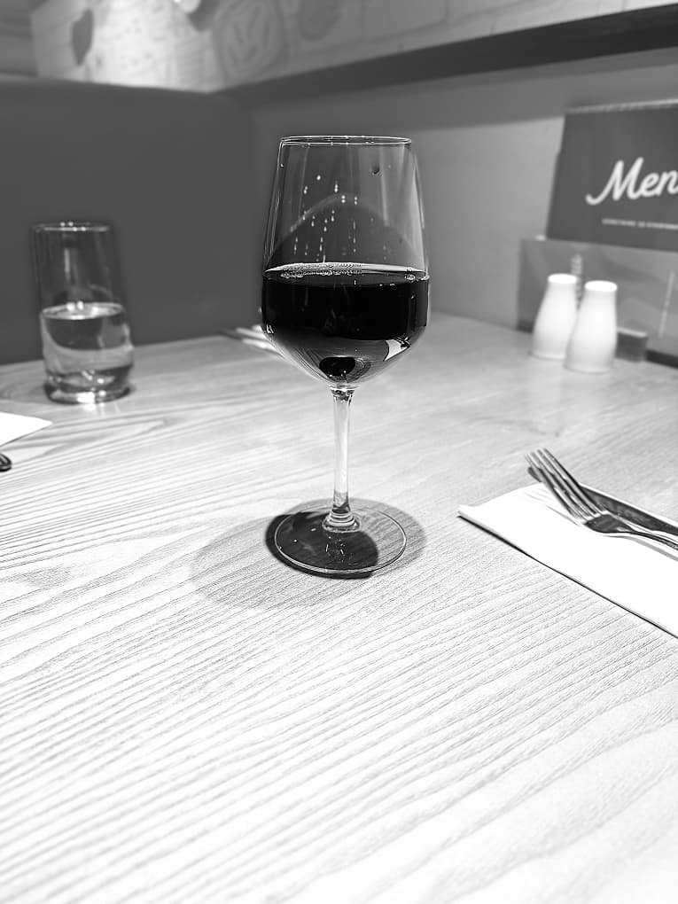 black-and-white photo of a glass of red wine on a restaurant table
