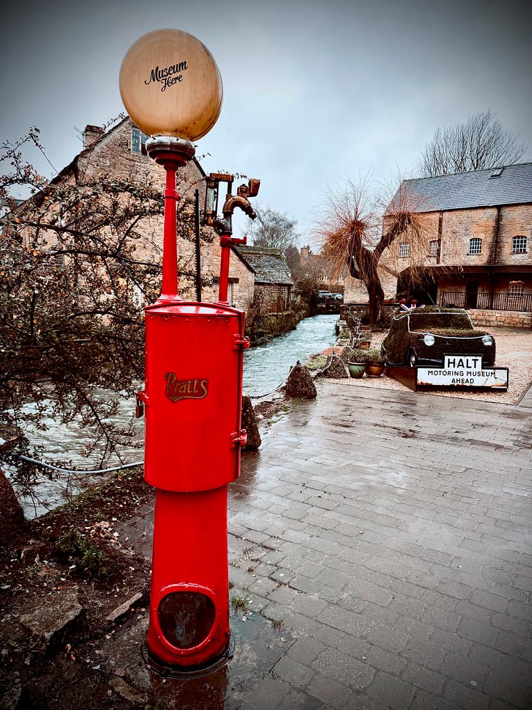 a red vintage petrol pump on a wet village street